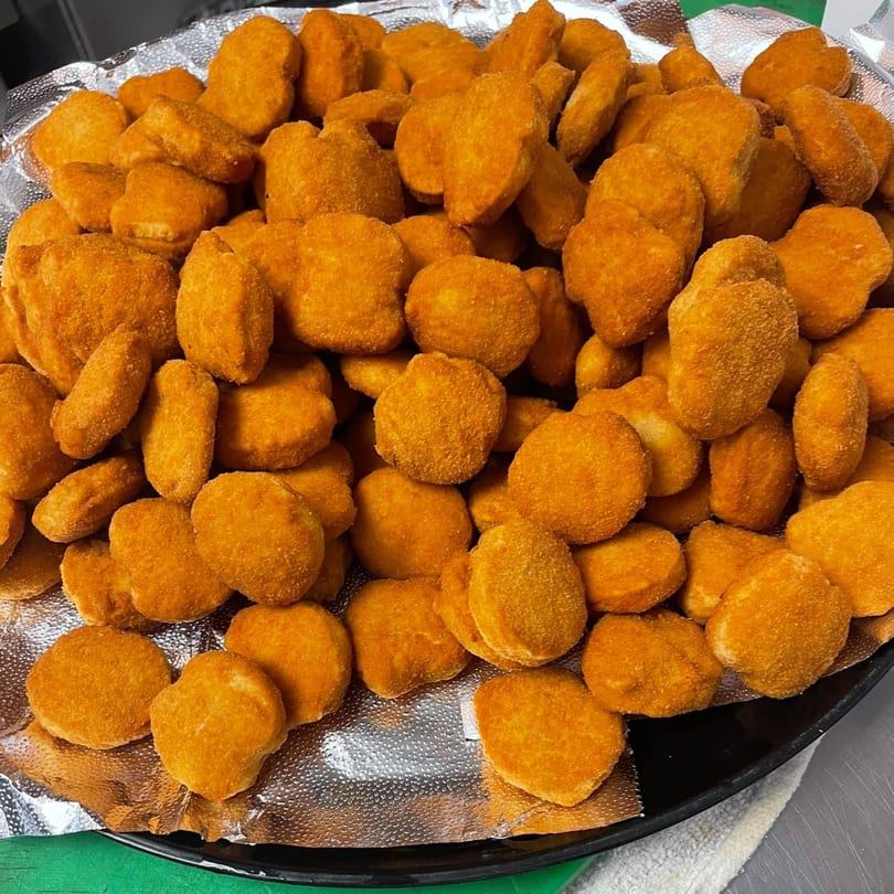 A large platter of golden-brown chicken nuggets, ready to be served at John's Famous Bagels & Deli.